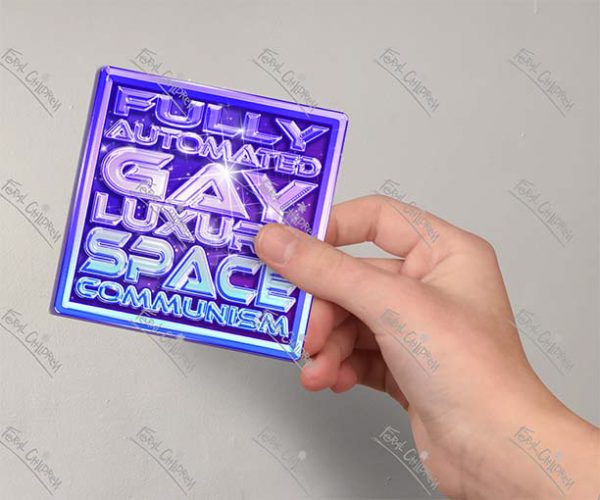 A glossy sticker of a purple and pink logo with the phrase "Fully Automated Gay Luxury Space Communism" in a shiny 3d futuristic styled font.